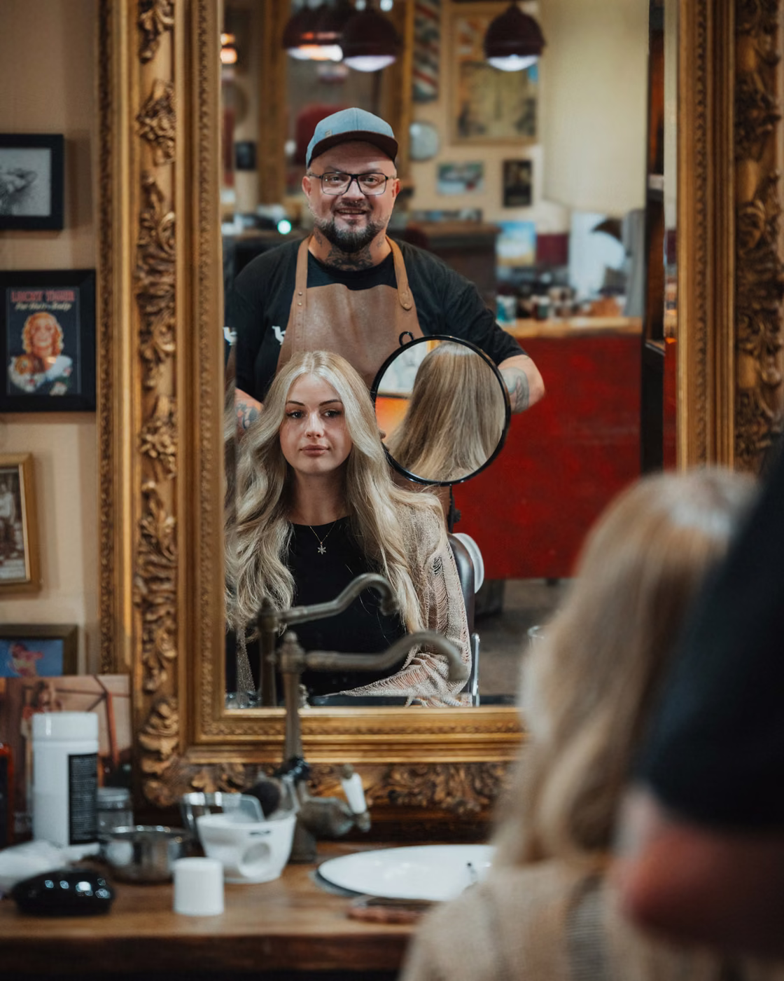 Friseurmeister Michael Lewandowski zeigt einer Kundin ihre blonde Balayage im Spiegel seines Arbeitsplatzes in Oldenburg